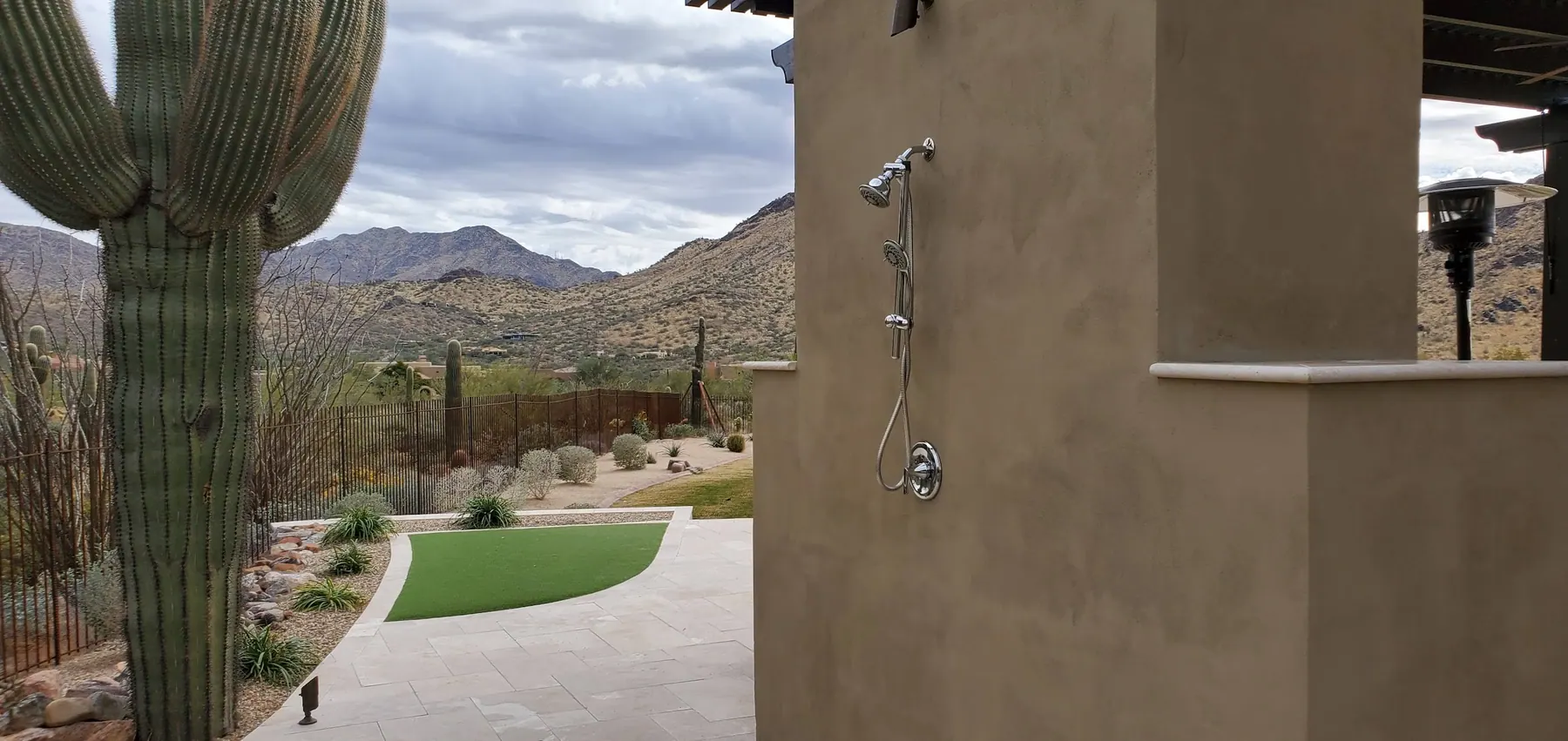 Outdoor shower on stucco wall with saguaro and mountain view